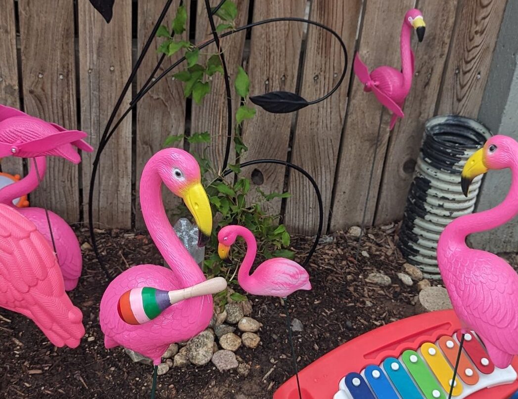 A fun flock of yard flamingos play on children's musical instruments!